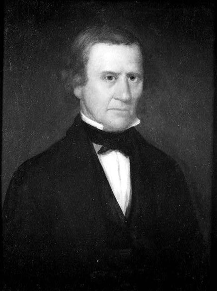 Older white man in suit with white shirt and black bow tie