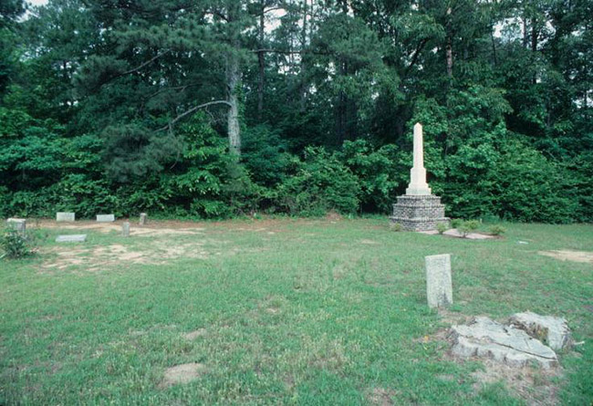 Gravestones and obelisk monument on three-tiered pedestal in cemetery