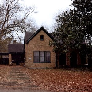 Brick house with covered porch and car port on leaf covered lawn