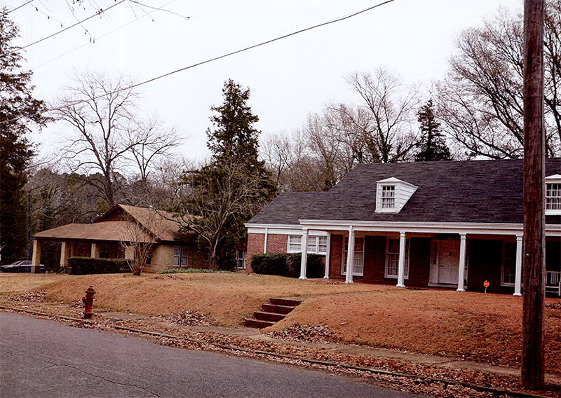 Single-story house with covered porch next to multistory house with covered porch on residential street