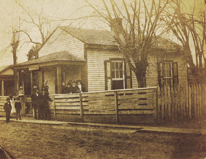Group of people outside building with wooden fence and trees