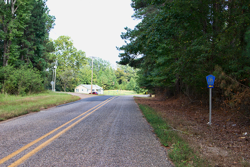 Two-lane rural road with single-story house in the background