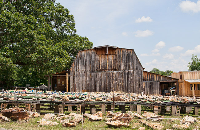 Rows of tables supported by concrete blocks with crystals and rocks with barn in the background