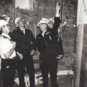 Three white men in helmets inside a complex