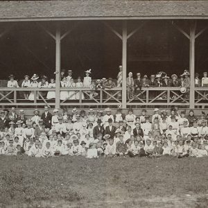Group of white men women and children gathered at large outdoor pavilion