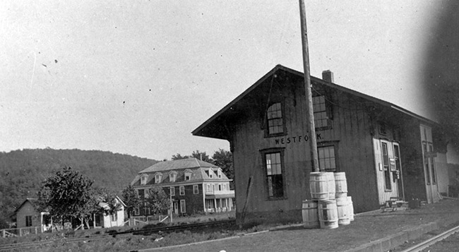Railroad depot building and tracks with town building in background
