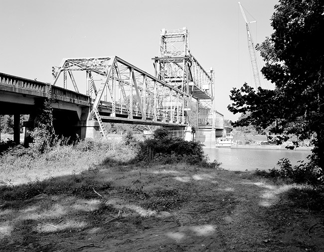 Steel lift bridge over river with concrete platform and supports