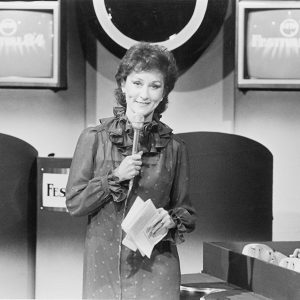 White woman with microphone on TV show set