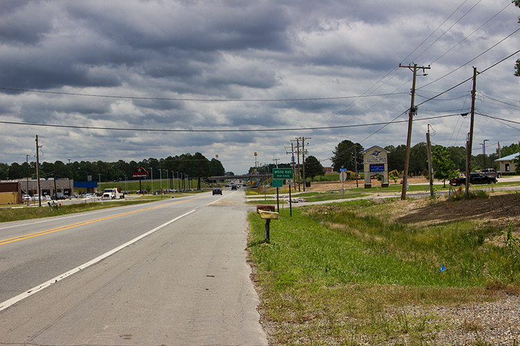 Two-lane highway through town under cloudy skies