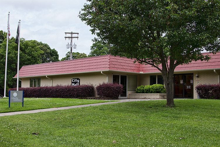 Single-story brick building with red roof and flag poles in front yard