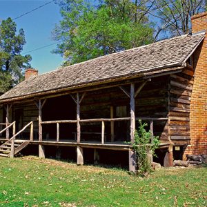 Log cabin with covered porch and brick chimneys