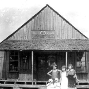 White man women and children posing outside general store