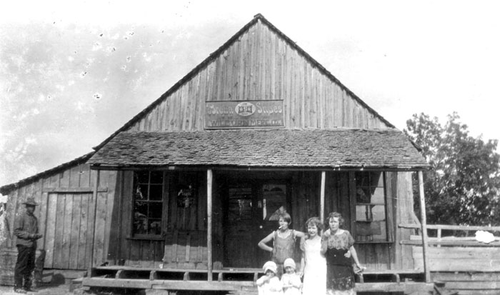 White man women and children posing outside general store