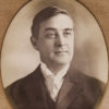 White man grinning in suit in oval frame