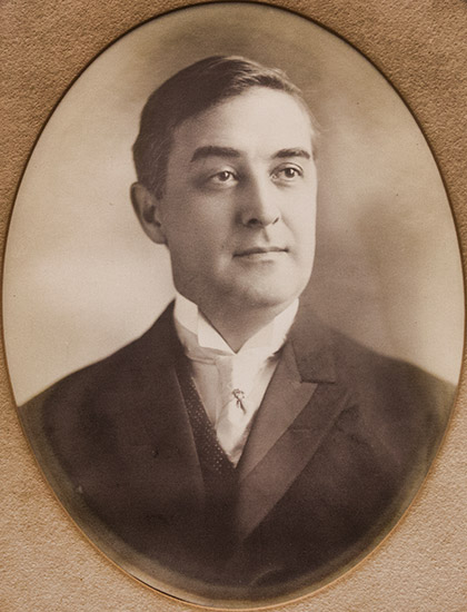 White man grinning in suit in oval frame