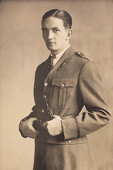 White man standing in military uniform with hands at his waist