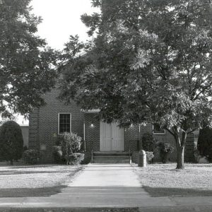 two-story brick building behind trees