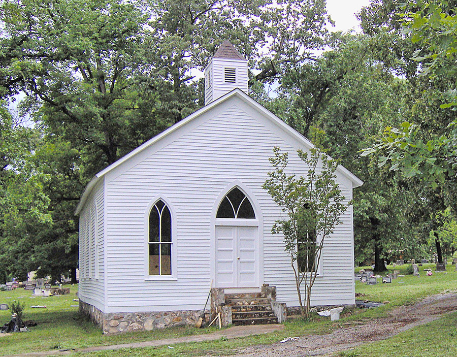 Restored church building with cupola and cemetery behind it