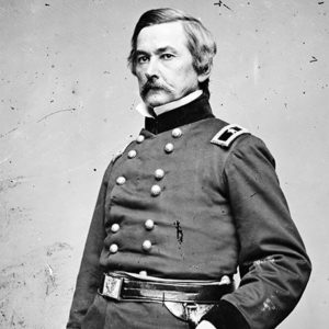White man with mustache standing in military uniform with sword
