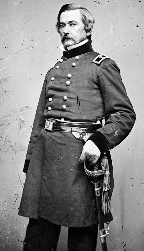 White man with mustache standing in military uniform with sword
