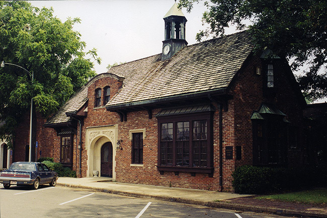Brick building with tower arched doorway and blue car in parking lot