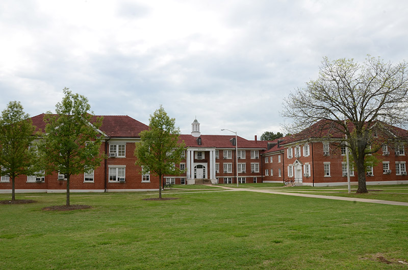 Multistory brick building with cupola and two wings on college campus