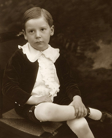 White boy sitting in collared shirt and shorts with legs crossed