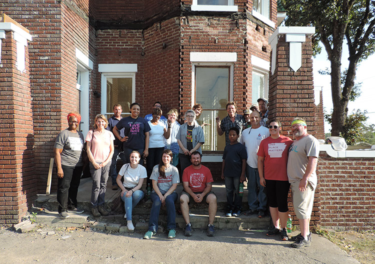 Mixed group of men and women in front of multistory brick house