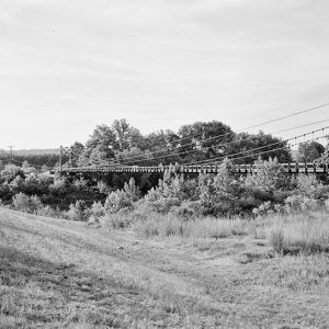 Steel suspension bridge as seen from dirt road nearby