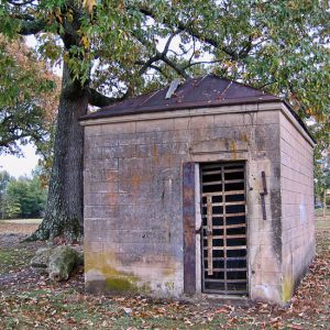 Small brick building with metal roof and bars on the door