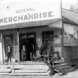 White men on porch of general store on dirt road