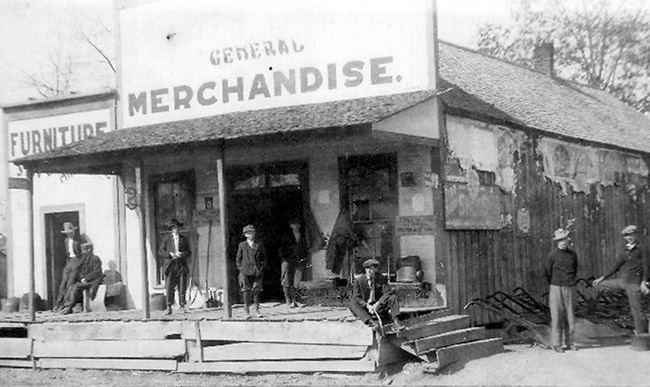 White men on porch of general store on dirt road
