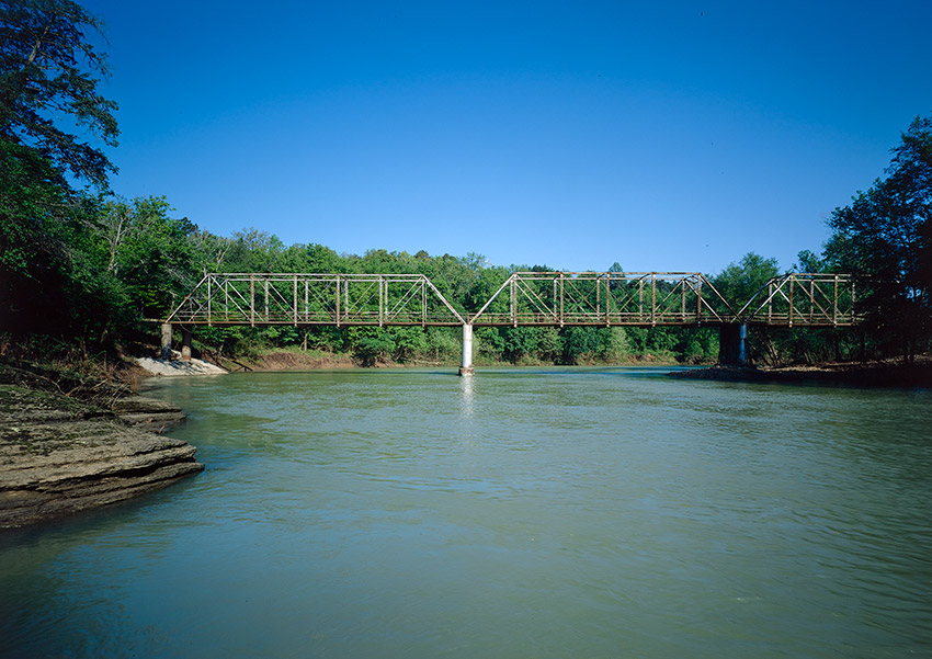 Bridge across a river with trees along the shoreline
