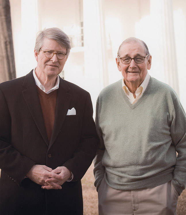 Two older white men with glasses smiling