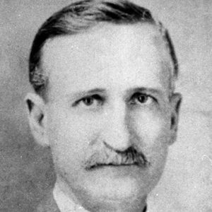 White man with mustache in suit jacket and tie