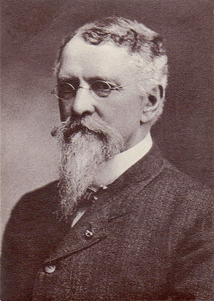 White man with glasses and beard in suit and bow tie