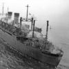 Large ship with two smoke stacks at sea with sprinkler system operating