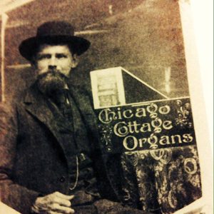 White man with long beard in hat and suit on "Chicago Cottage Organs" advertisement