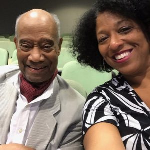 Older African-American man smiling alongside African-American woman in theater seats