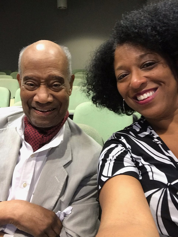 Older African-American man smiling alongside African-American woman in theater seats