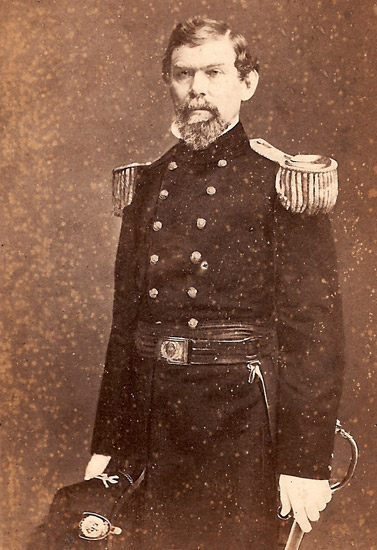 White man with mustache standing in military uniform with sword in his left hand and hat in his right hand
