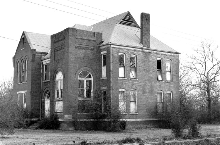 Two-story brick building with arched windows and arched doorway