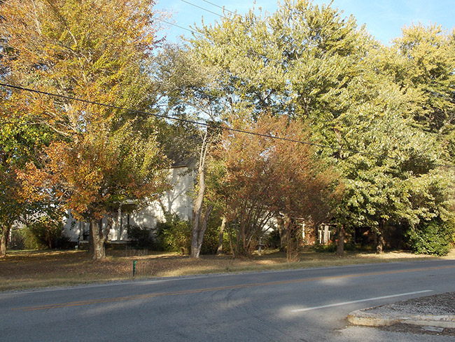 Multistory house behind autumn trees on street