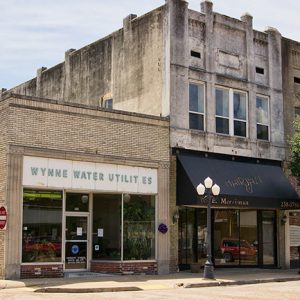 Single-story "Wynne Water Utilities" building and two-story store fronts on street