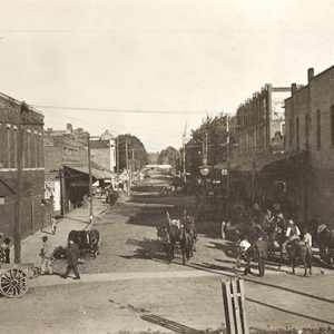 Horse drawn wagons and people walking on town street