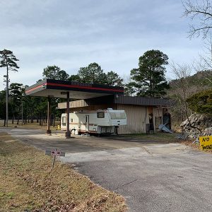 RV trailer at abandoned gas station with canopy and parking lot