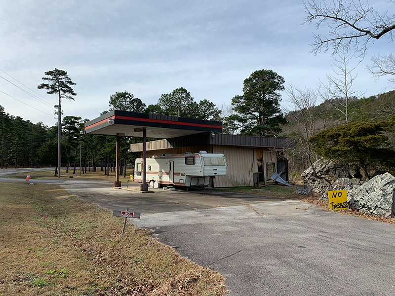 RV trailer at abandoned gas station with canopy and parking lot