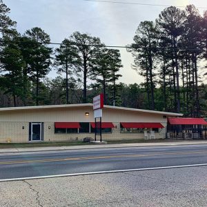 Single-story building with sign and red awnings on highway