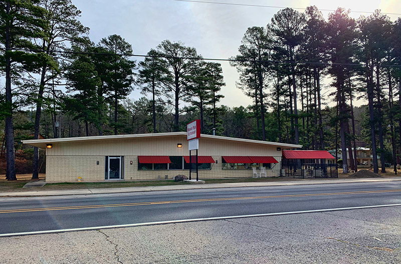 Single-story building with sign and red awnings on highway