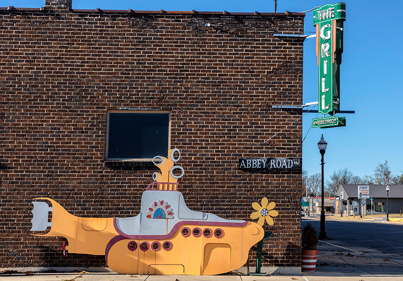 Cartoonish yellow submarine sculpture and Abbey Road sign on side of "The Grill" restaurant building